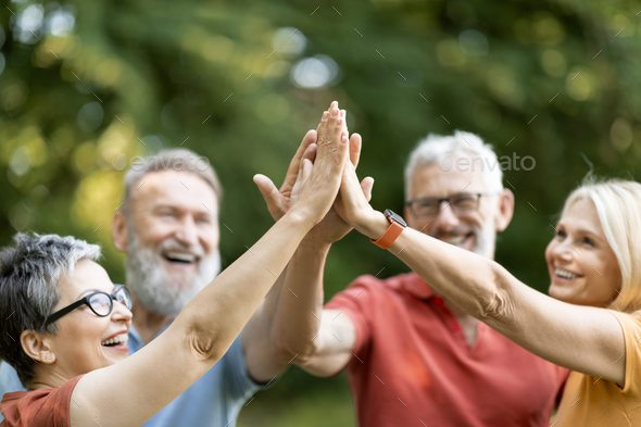 Portrait Of Happy Mature People Giving High Five To Each Other Outdoors